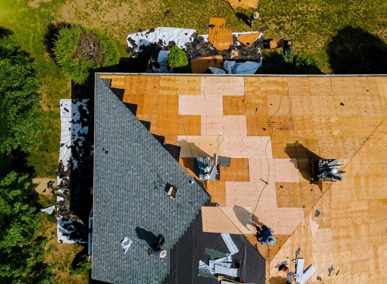 Sunlit asphalt shingles with faded areas, curled edges, and granules collected in a nearby gutter.